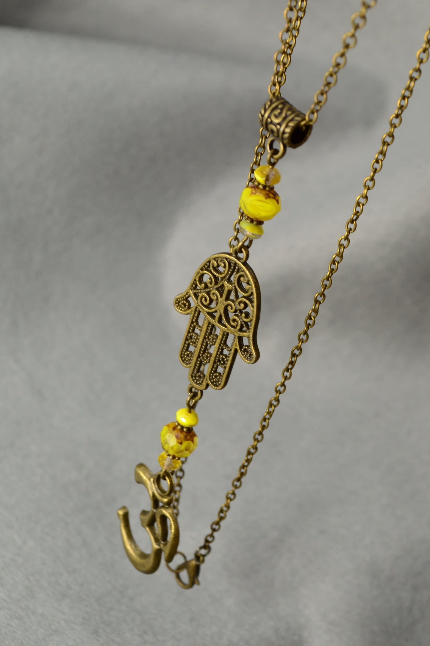 Hamsa hand & Ohm sympol pendant. Bronze Chain Necklace Adorned with Yellow Glass Beads and Spiritual Pendants