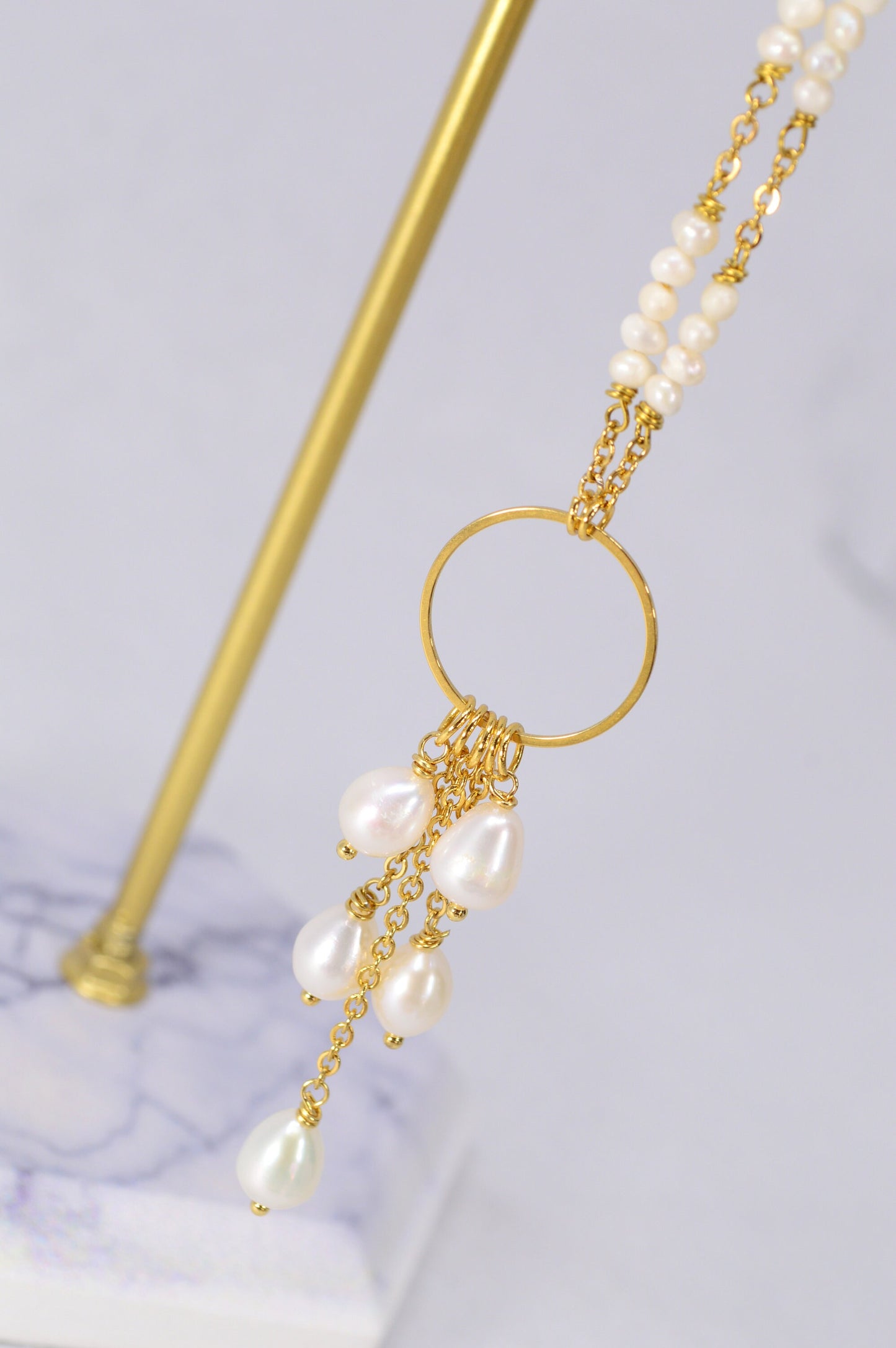 Elegant golden necklace adorned with freshwater pearls and baroque pearls in a unique triangular design. Estibela design.