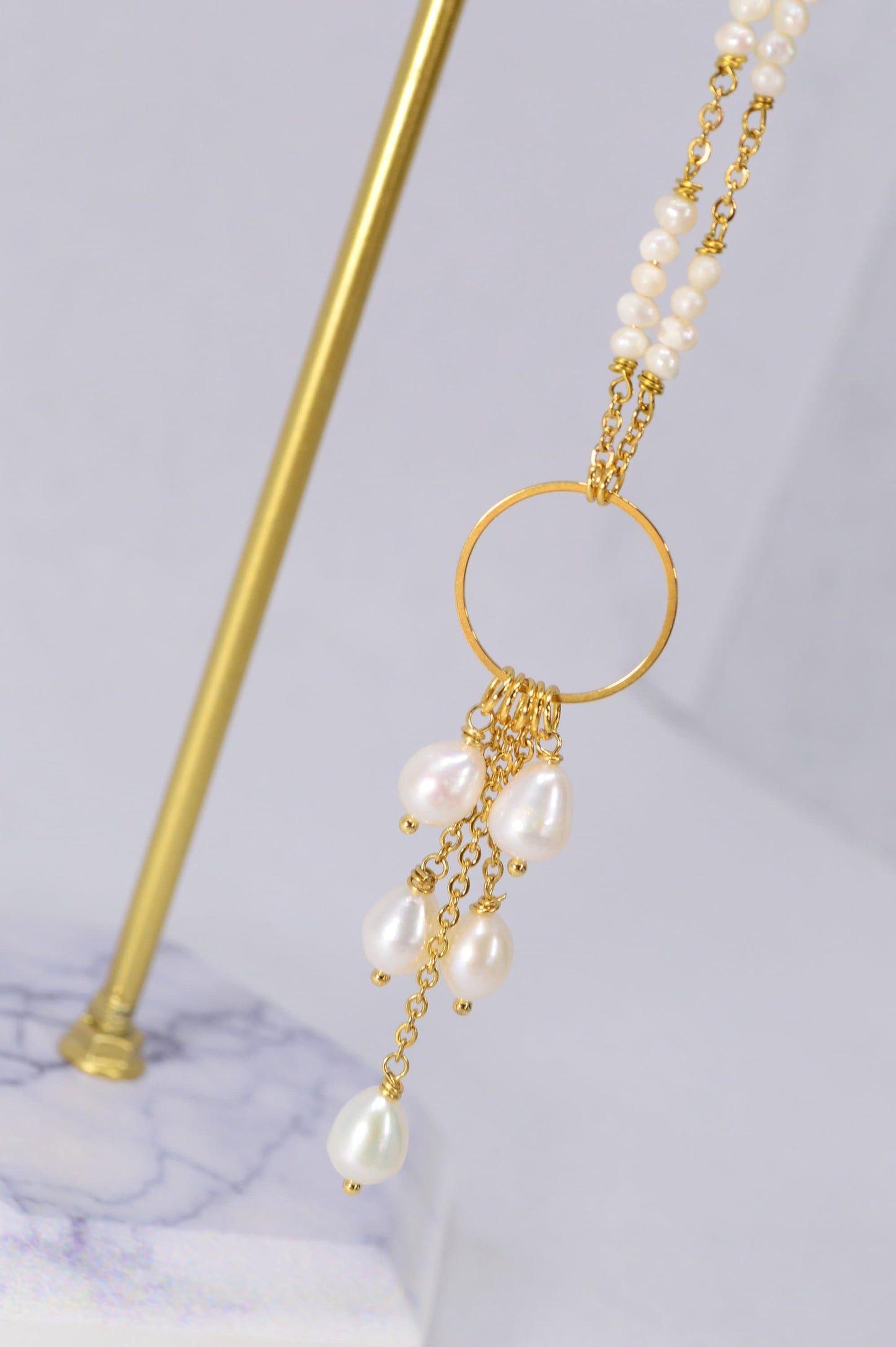 Elegant golden necklace adorned with freshwater pearls and baroque pearls in a unique triangular design. Estibela design.