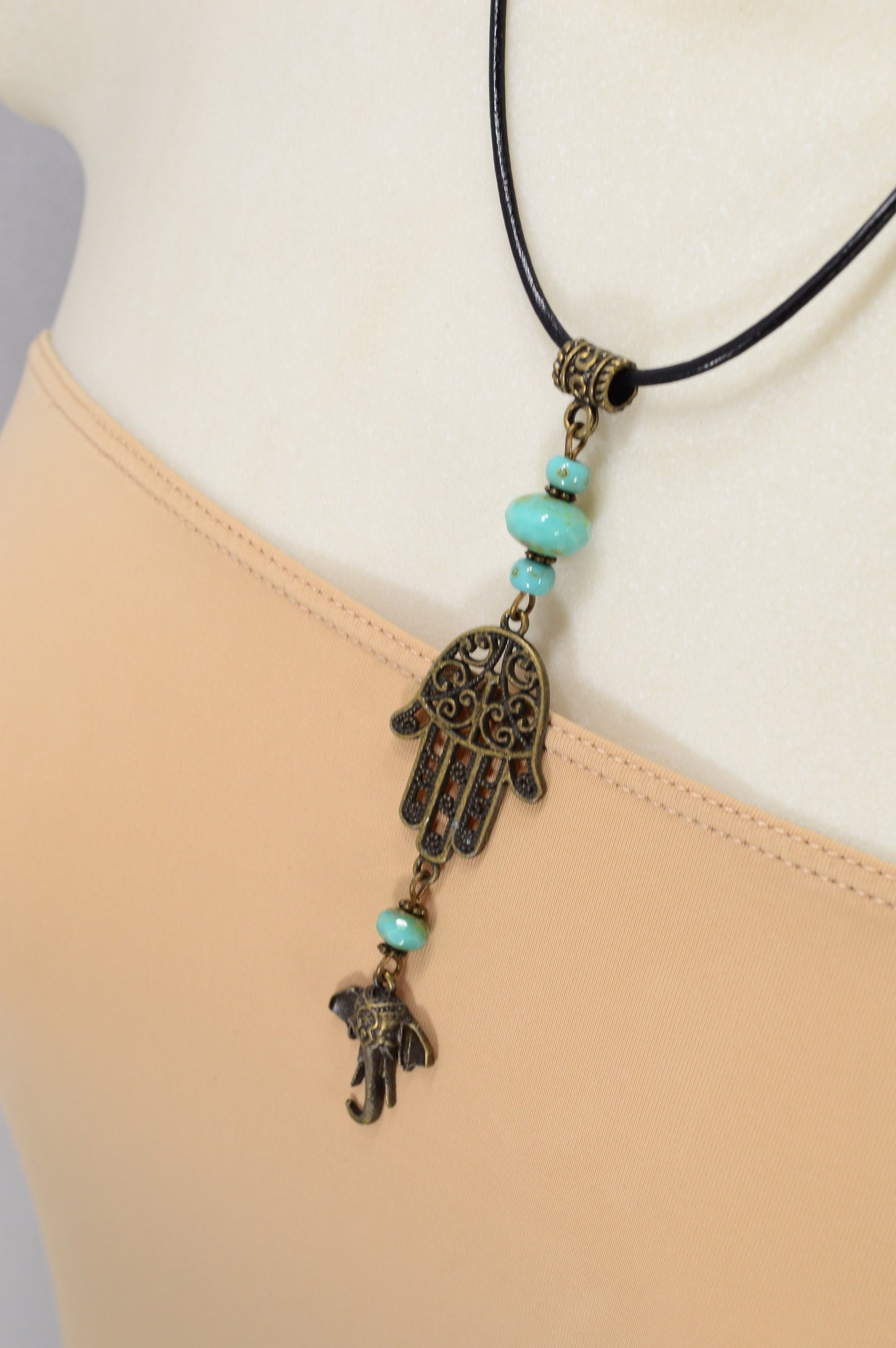 Boho chic leather cord with intricate bronze pendant & sea green Czech glass, perfect for adding flair to any outfit. Estibela design.