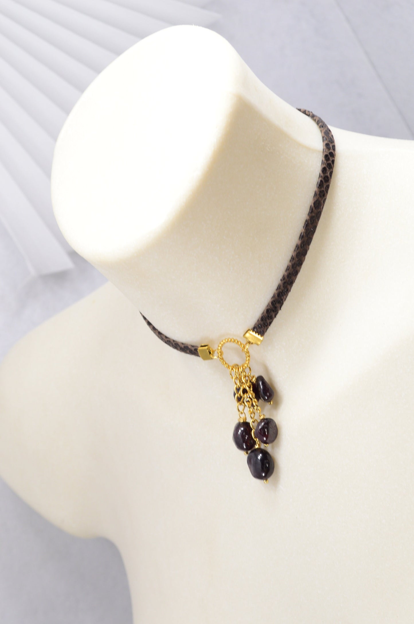 Brown leather choker with unique Estibela design. Stainless steel ring and cascading garnet beads. Limited edition.