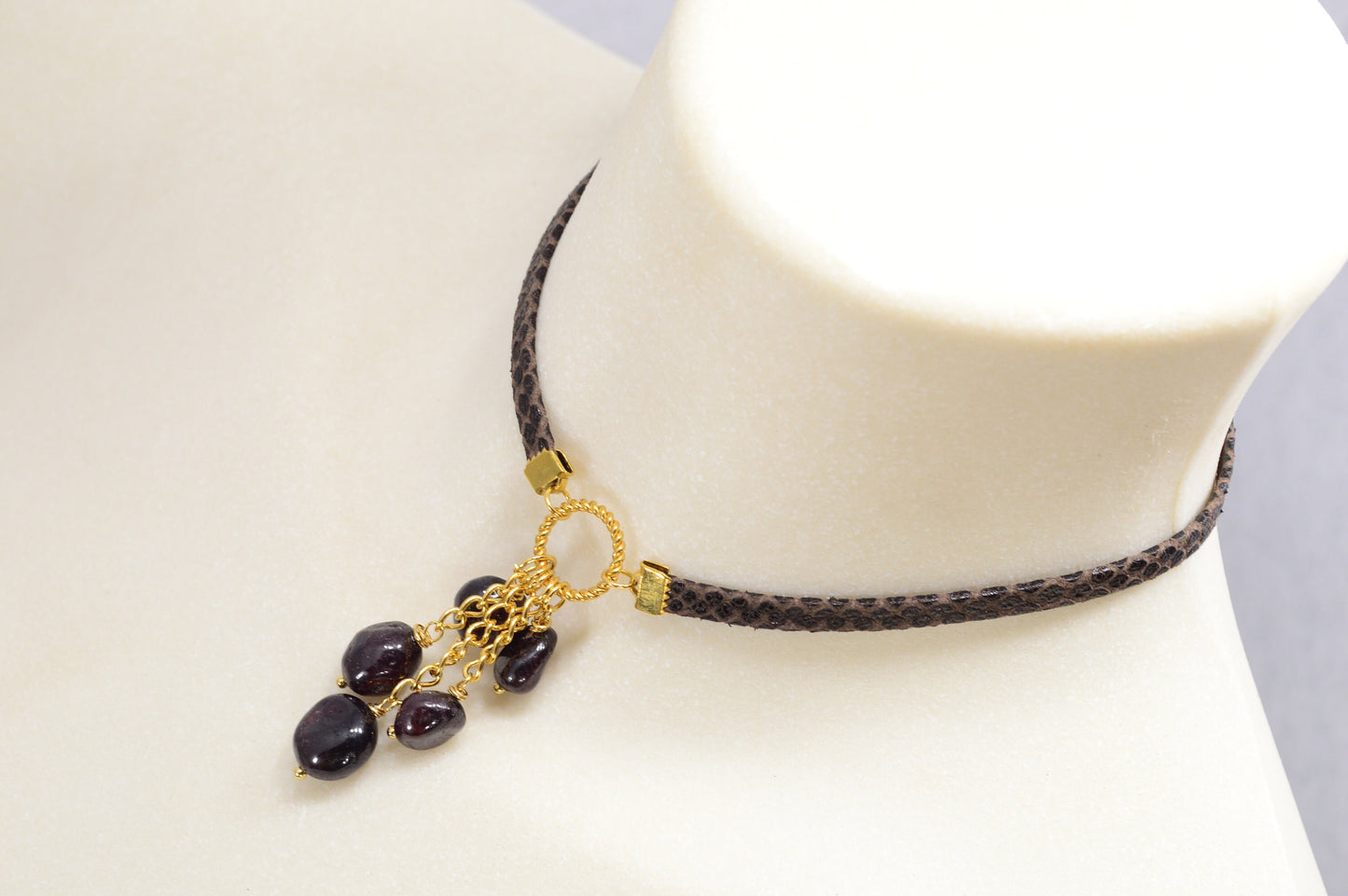 Brown leather choker with unique Estibela design. Stainless steel ring and cascading garnet beads. Limited edition.