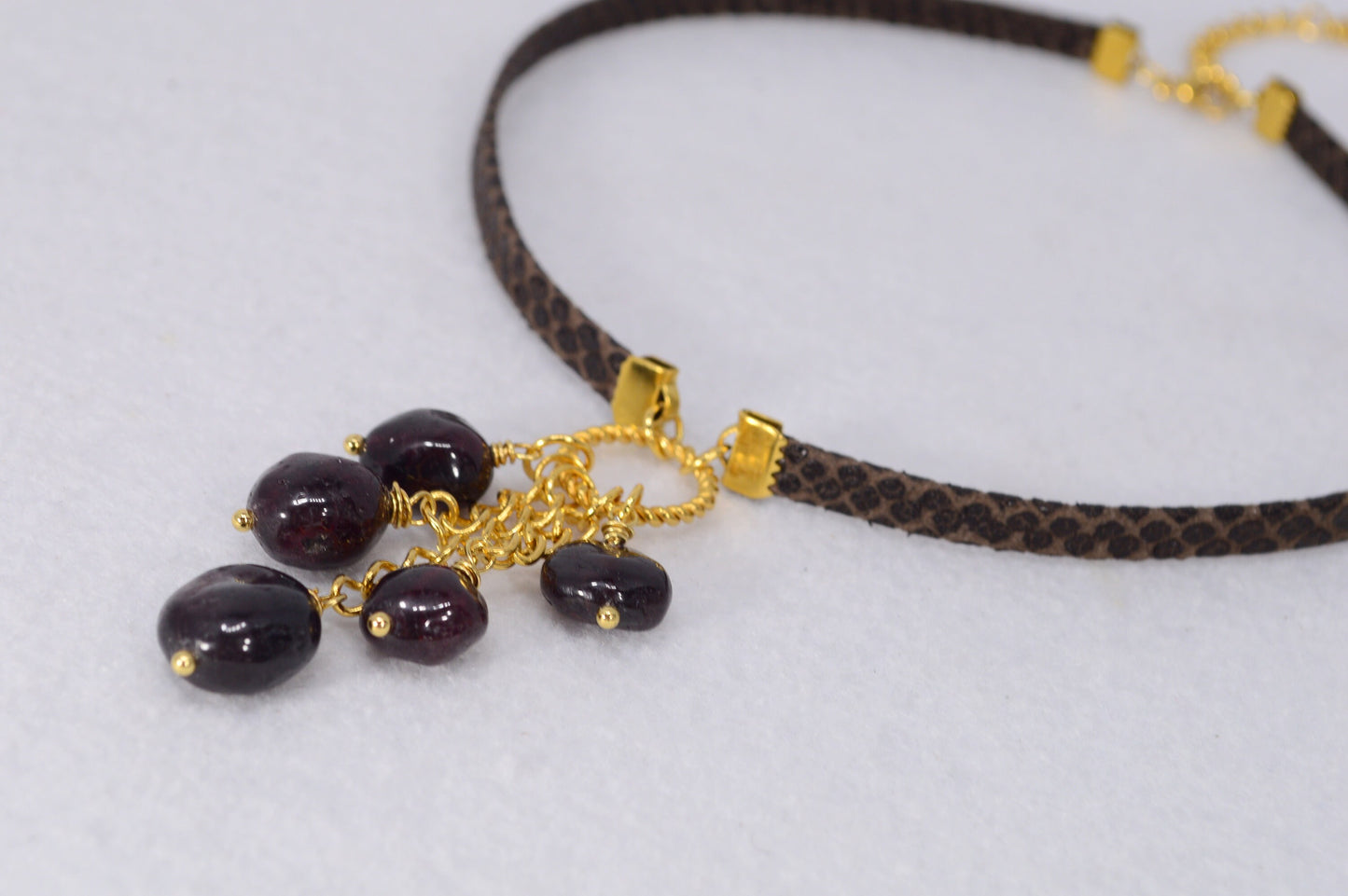 Brown leather choker with unique Estibela design. Stainless steel ring and cascading garnet beads. Limited edition.