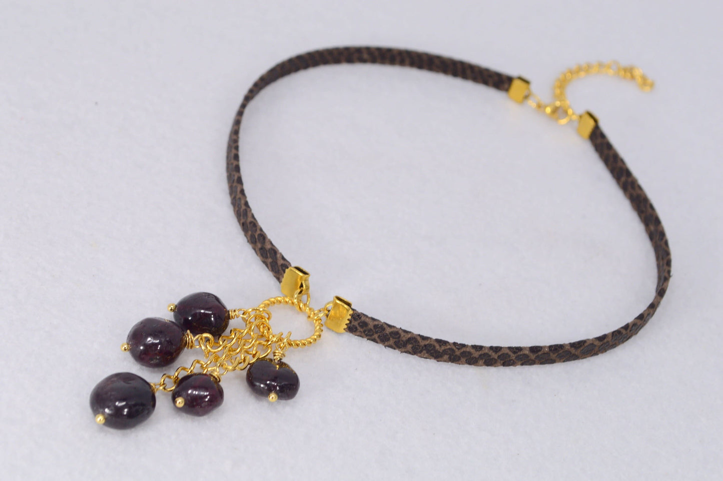 Brown leather choker with unique Estibela design. Stainless steel ring and cascading garnet beads. Limited edition.